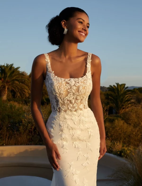 Robe de mariée en dentelle avec dos plongeant et surjupe transparente brodée, photographiée dans un jardin au coucher du soleil.