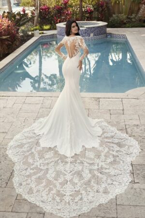 Robe de mariée sirène en satin fluide avec manches longues en tulle brodé et traîne cathédrale ornée de motifs floraux.