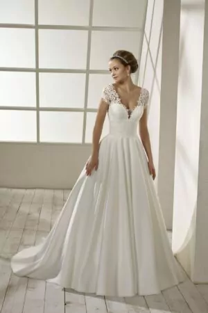 Robe de mariée en crêpe blanche avec corsage en dentelle, manches courtes, dos plongeant et jupe fluide avec traîne légère.