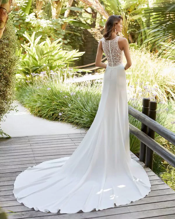 Robe de mariée Adriana Allier en crêpe, dos illusion en dentelle et col en V, photographiée dans un jardin tropical.