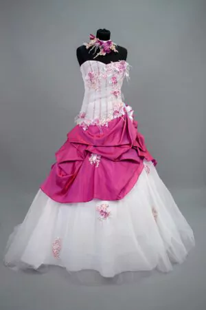 Robe de mariée Allure Annie Couture en blanc et fuchsia, avec un bustier drapé en tulle, des détails floraux et une jupe volumineuse, idéale pour un mariage audacieux et mémorable.