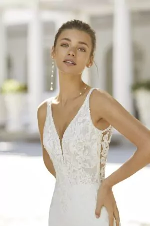 Robe de mariée élégante en crêpe avec corsage en dentelle, décolleté en V plongeant et dos boutonné.