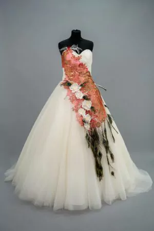 Robe de mariée bustier princesse avec broderie florale orange et corail, ornée de plumes de paon et d'un motif unique, vue de face.