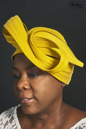 Bandeau turban jaune vibrant avec boucles stylisées, porté par une femme, disponible chez Christiane Boutique.