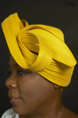 Bandeau turban jaune vibrant avec boucles stylisées, porté par une femme, disponible chez Christiane Boutique.