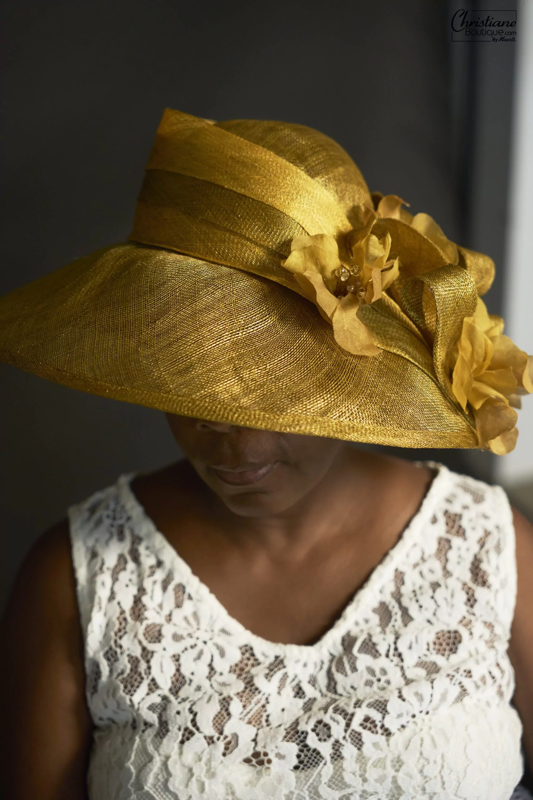 Chapeau en sisal naturel doré avec large bordure et détails floraux, idéal pour mariages et événements en extérieur.