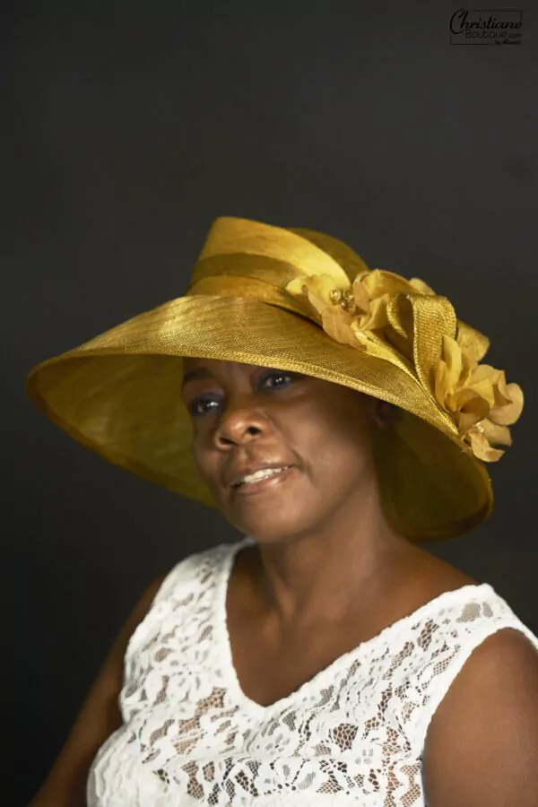 Chapeau en sisal naturel doré avec large bordure et détails floraux, idéal pour mariages et événements en extérieur.