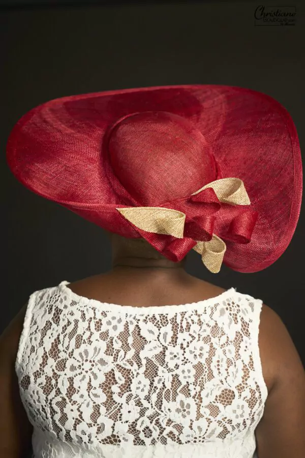 Chapeau large en paille rouge orné d'un nœud doré, fabriqué artisanalement par Christiane Boutique.