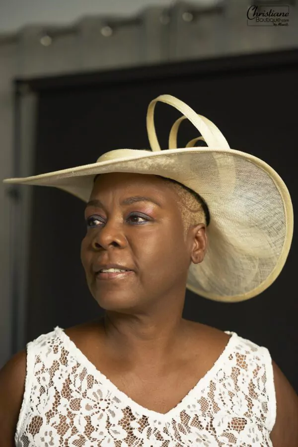 Chapeau en paille ivoire avec boucles et fleurs, conçu artisanalement par Christiane Boutique. Pièce unique pour une élégance intemporelle.