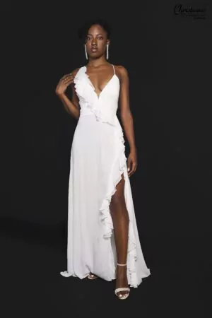 Robe fluide blanche à dos nu avec bretelles croisées et volants, parfaite pour un mariage décontracté et élégant.